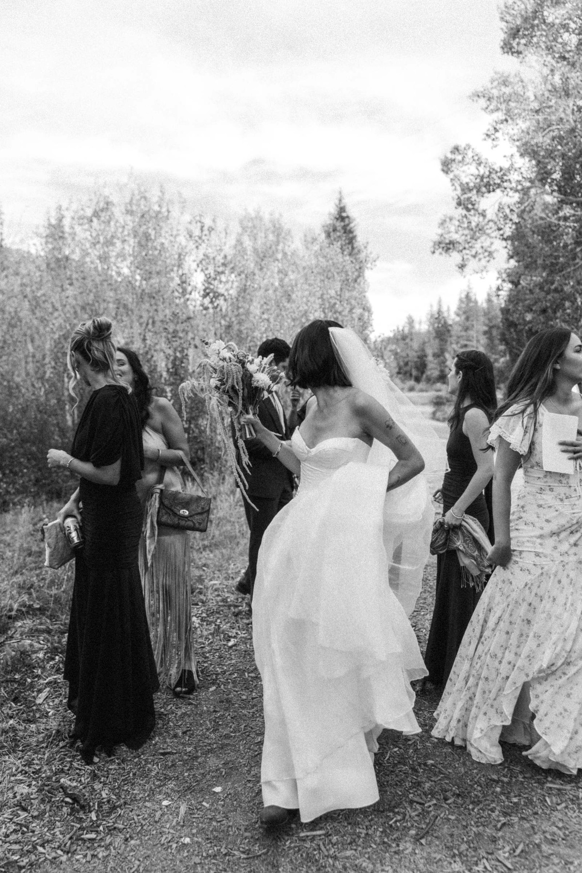 Devin's friends embrace her after the ceremony on the trail at a mountain ranch among the aspens, black and white