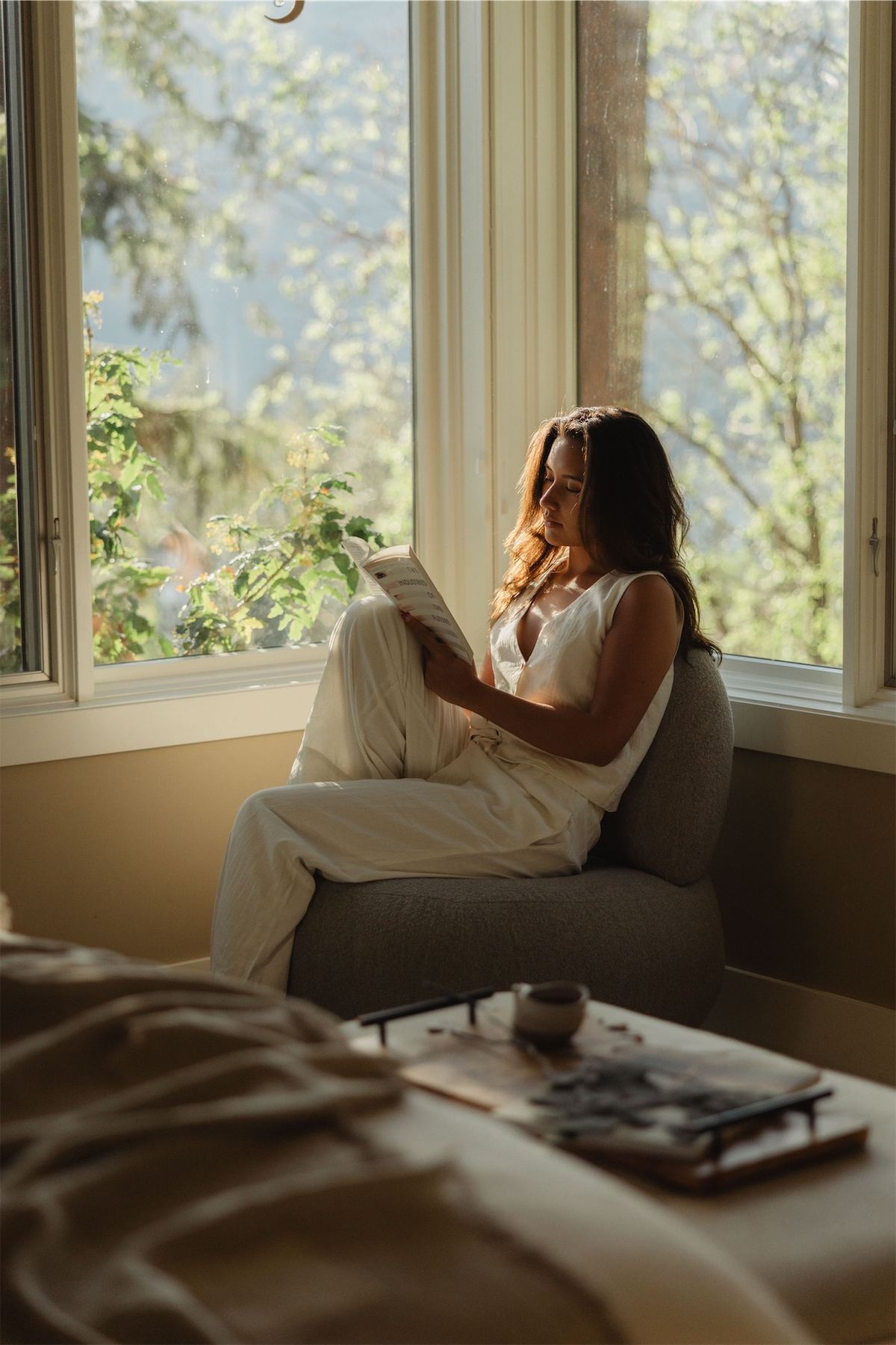 Woman reading in a window seat with the lake and treetops beyond