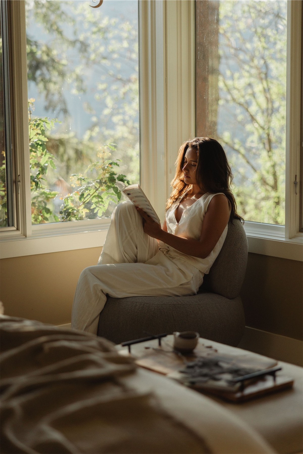 Woman reading in a window seat with the lake and treetops beyond