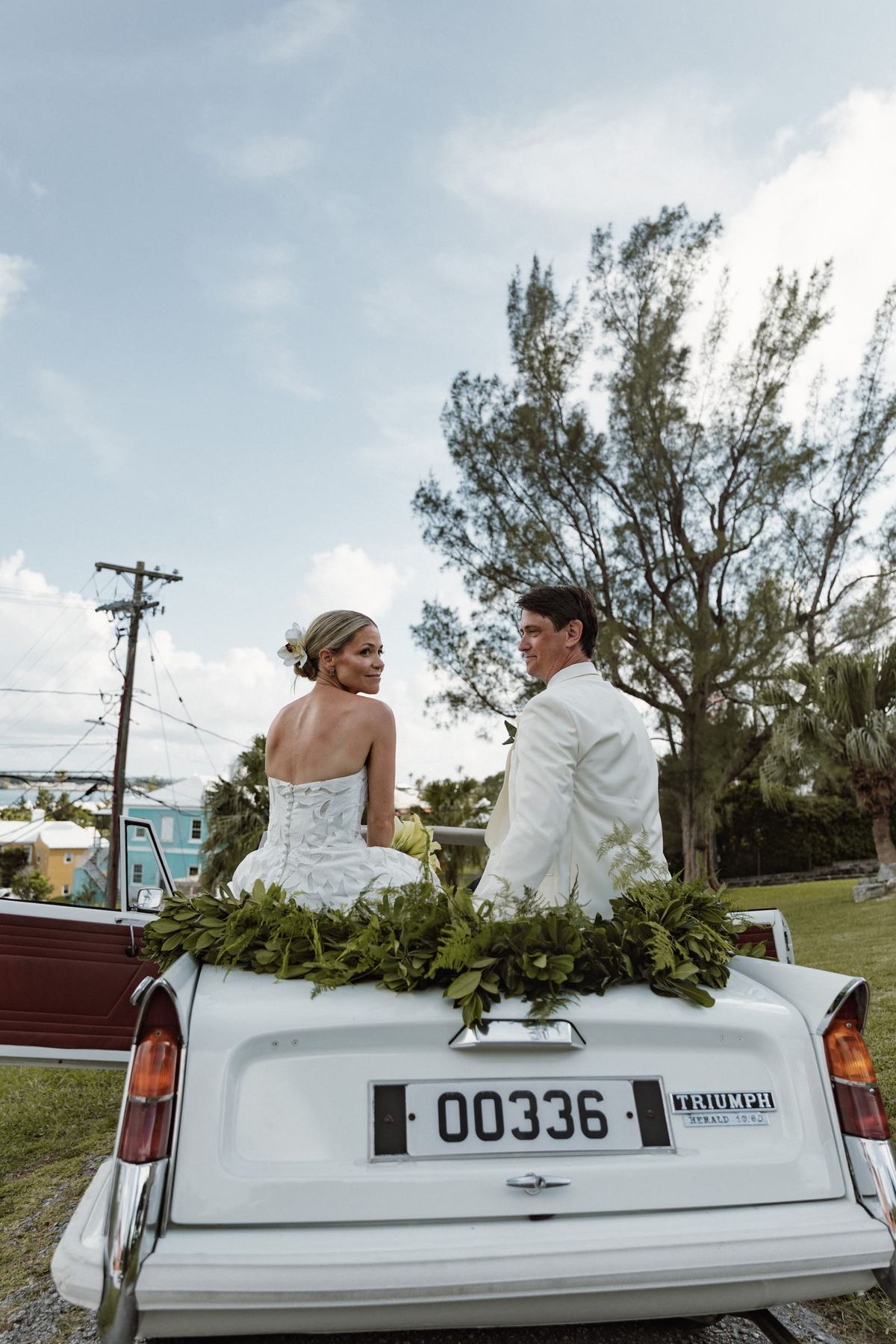 Bride and groom on the back of a white vintage convertible in Bermuda
