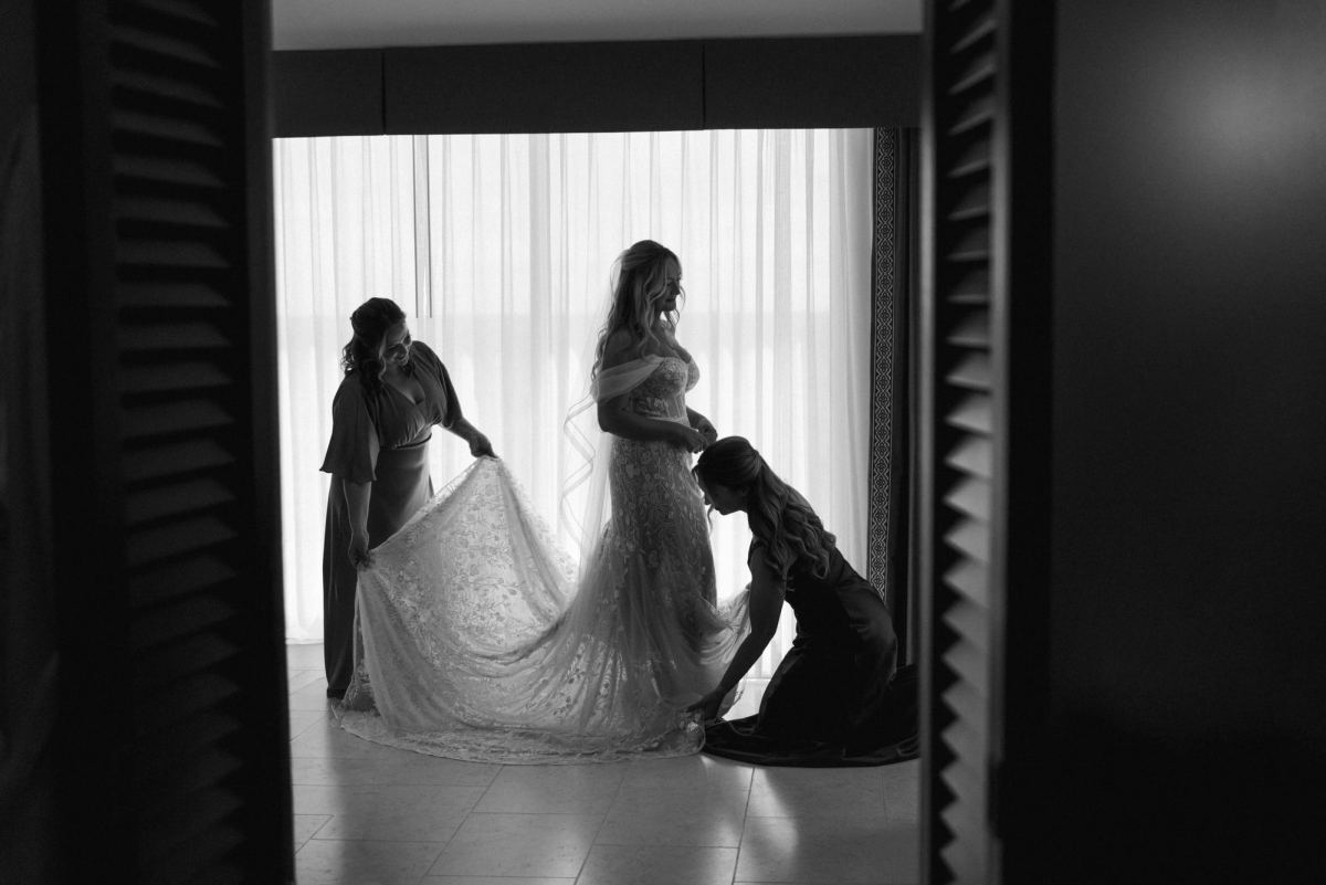 Black and white photograph of bride being dressed in doorway at Bermuda wedding