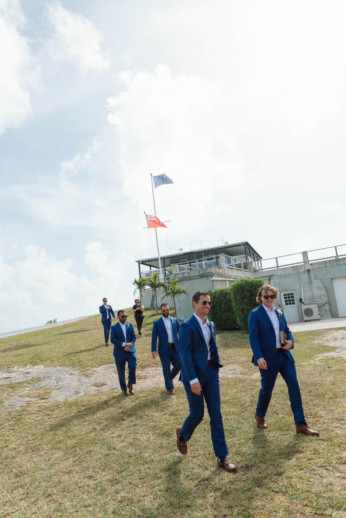 Groomsmen stride across the grass toward the ceremony on Hawkins Island, Bermuda