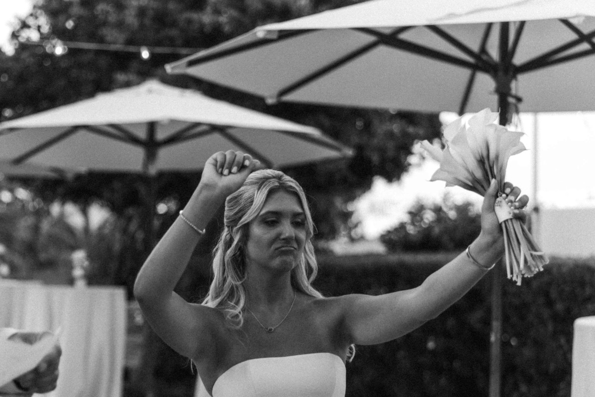 Paige throws her arms up with her bouquet at the reception entrance on Hawkins Island, Bermuda, black and white