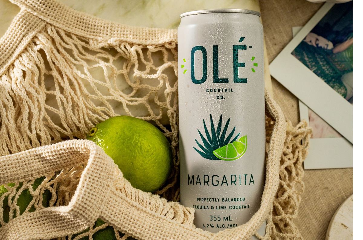 Close crop of the margarita can tucked into a mesh tote bag with a fresh lime
