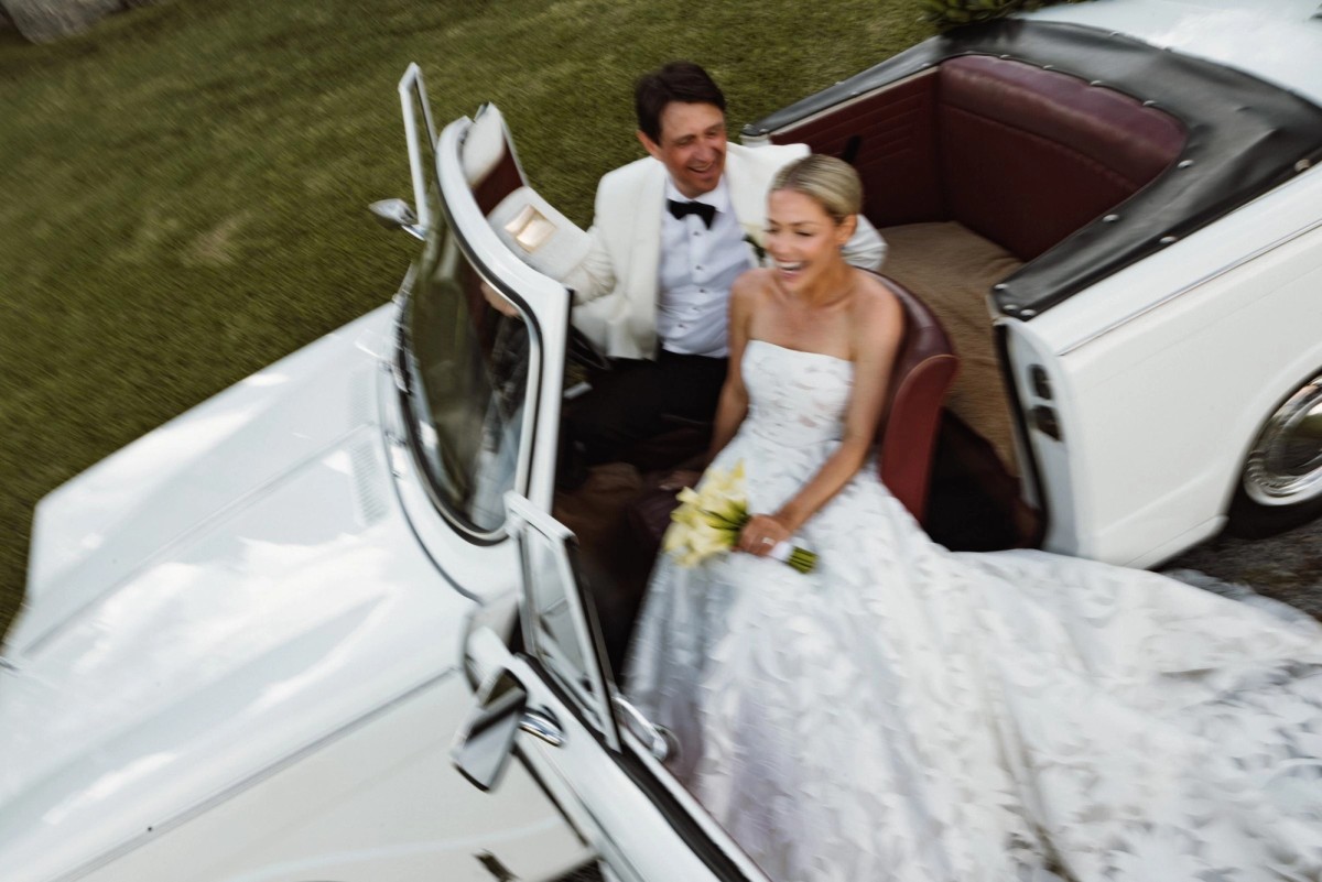 Bride and groom laughing in a white vintage convertible after their Bermuda wedding