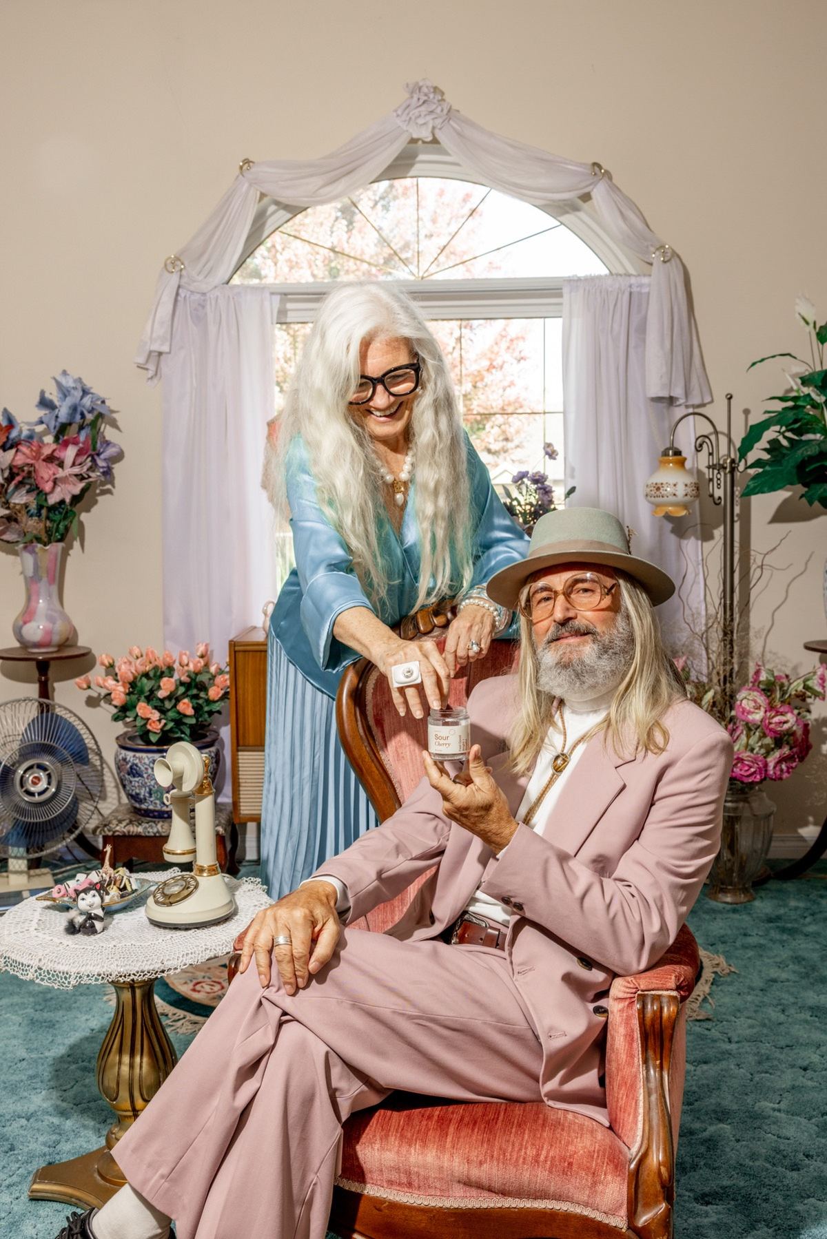 Older couple posing with a capsule jar in a floral vintage sitting room