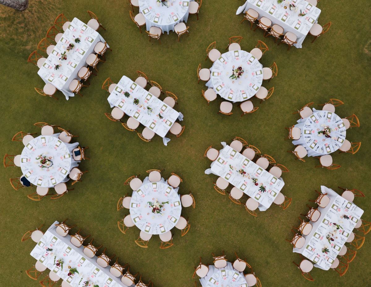 Aerial view of the reception tables set on the lawn above the beach
