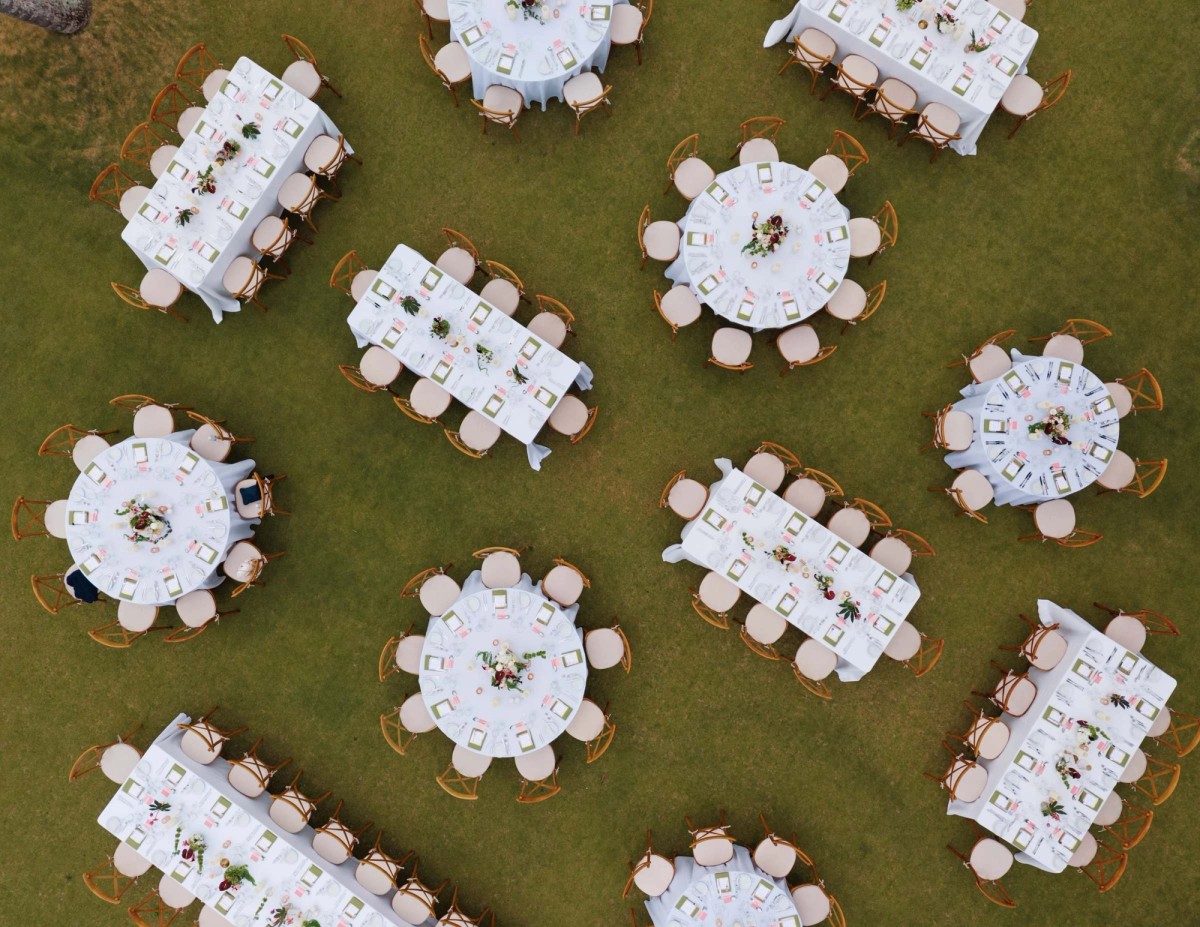 Aerial view of the reception tables set on the lawn above the beach