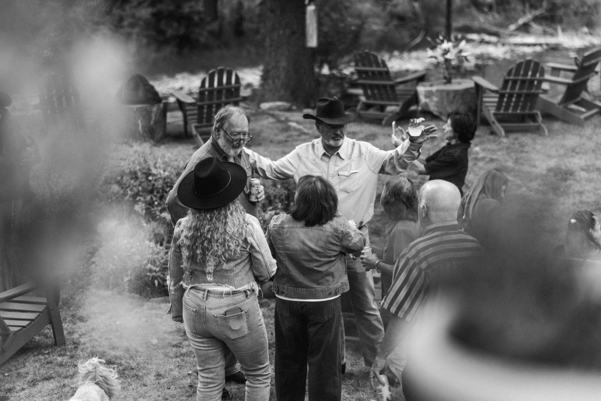 A guest raises a glass in the garden at the welcome dinner at a mountain ranch among the aspens, black and white