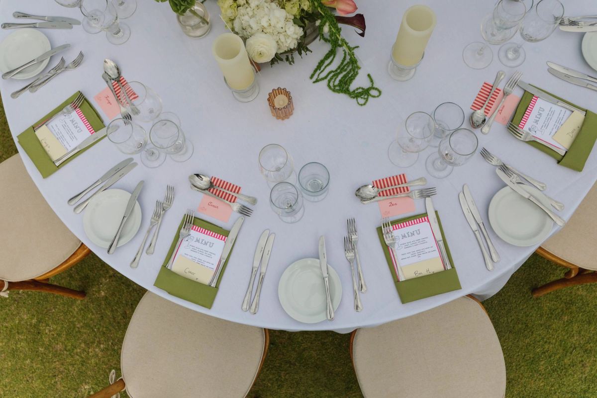 Overhead view of a round reception table with green menus and candlelight