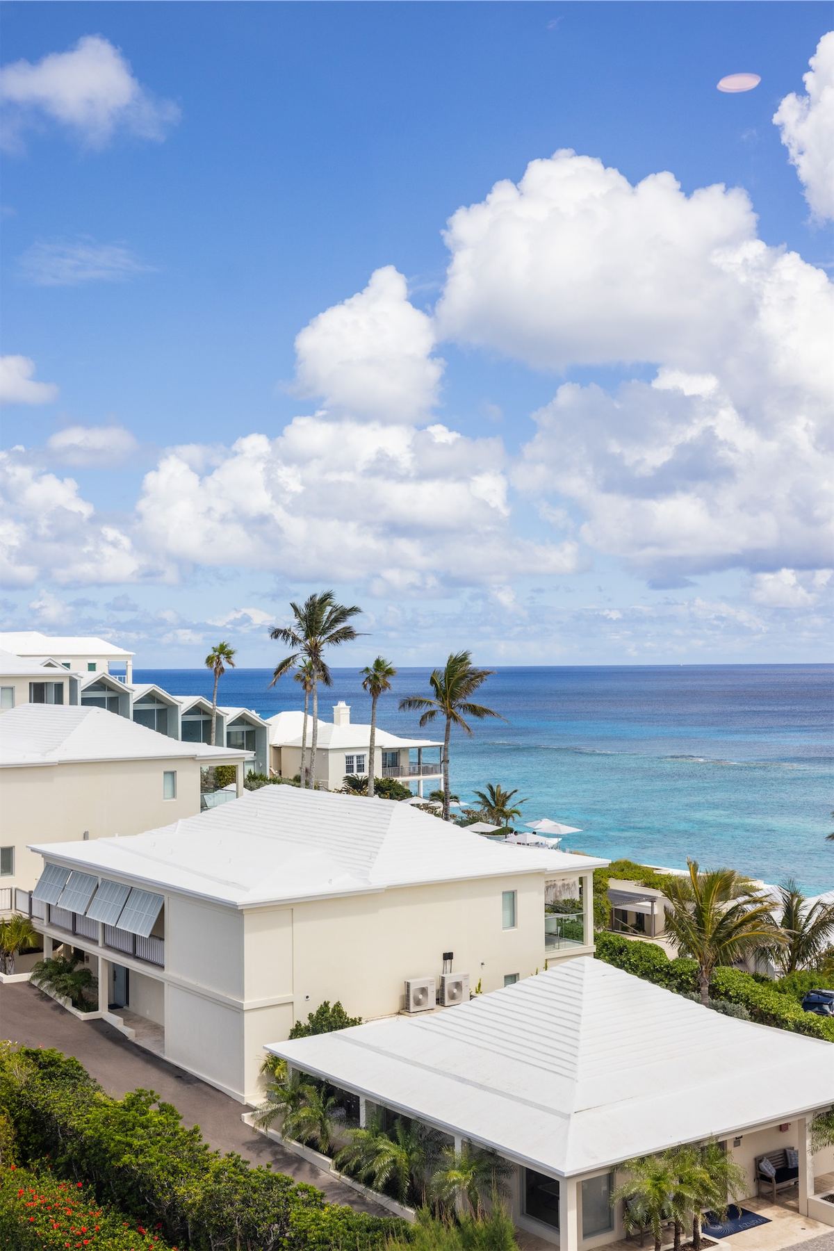 View across white resort rooftops and palms toward the turquoise water