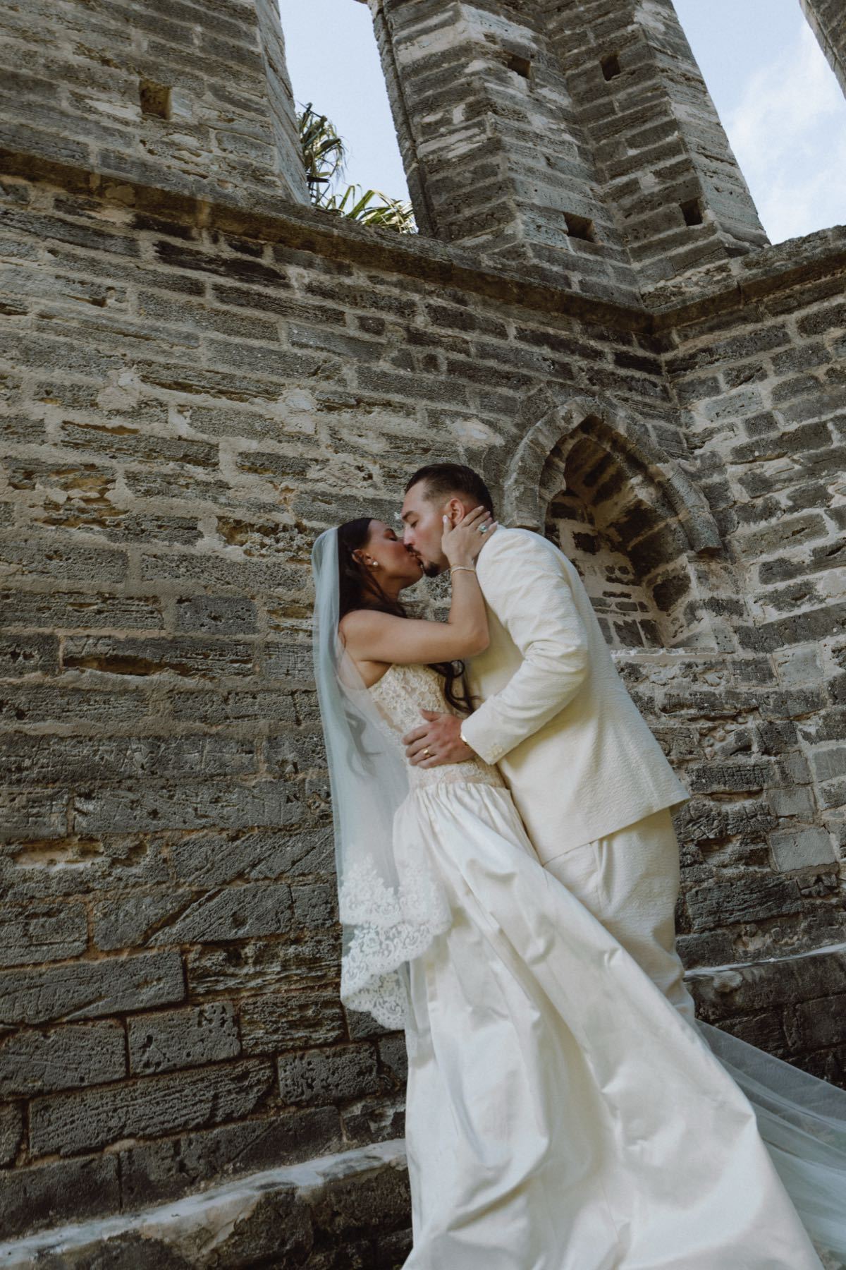 Cinematic low angle kiss between bride and groom at gothic stone ruins Bermuda wedding