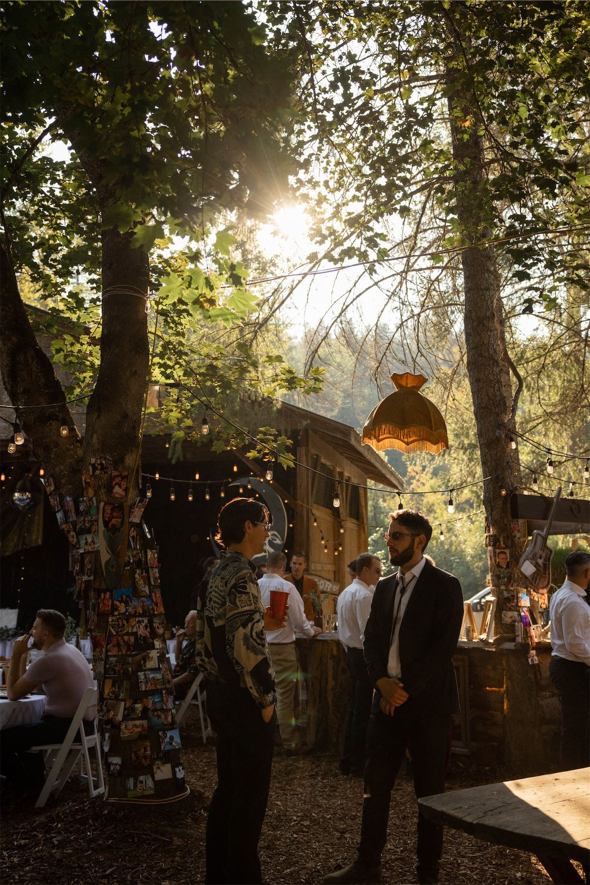 Guests mingling through the woodland reception area at golden hour