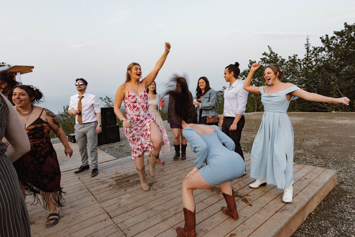 Guests dancing on the wooden deck at a mountaintop wedding reception