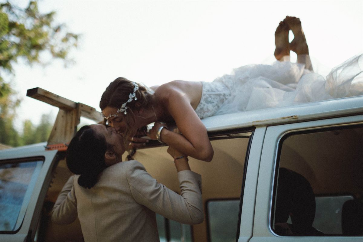 One bride leaning down from the camper roof to kiss the other