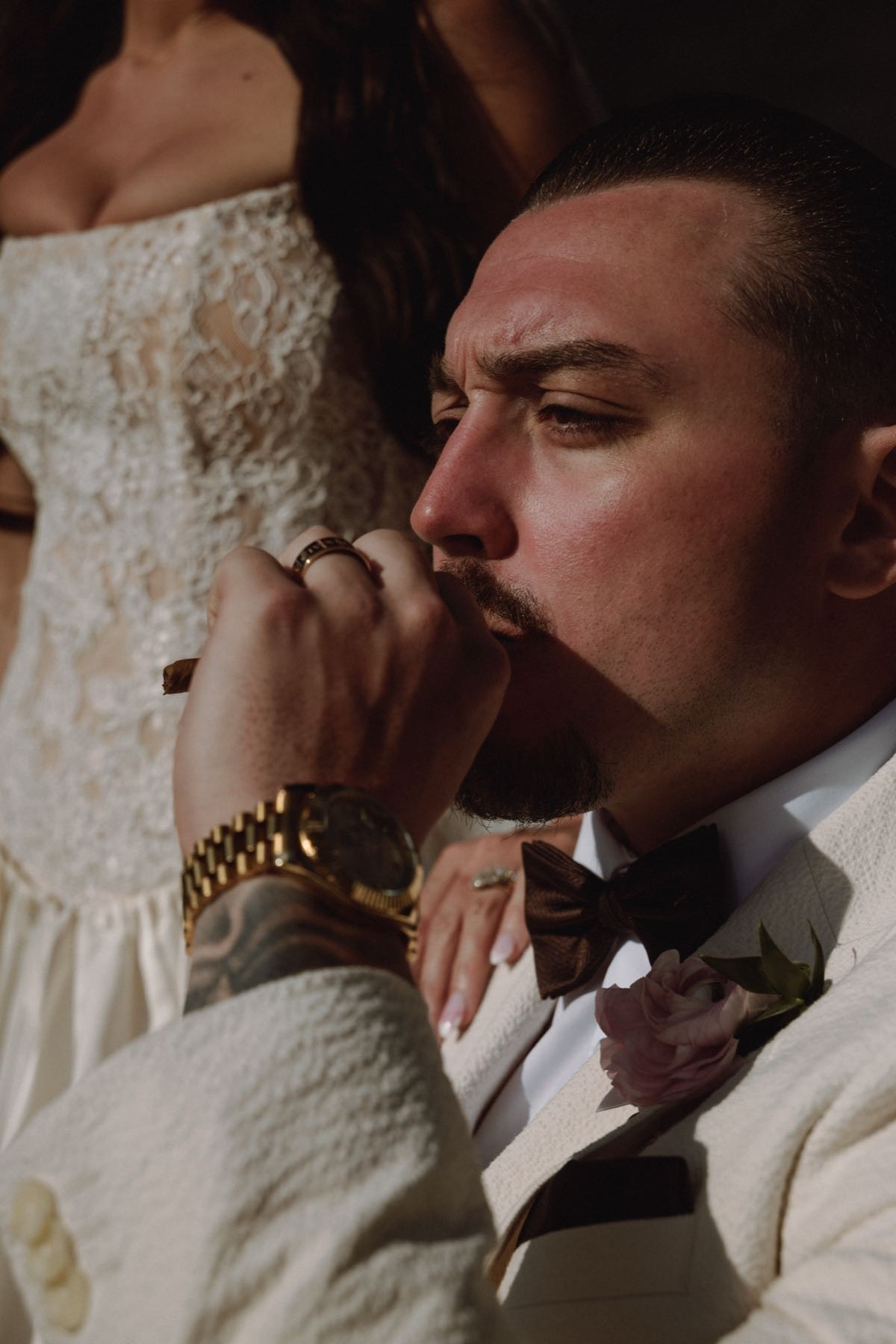 Tender close-up of bride's hand with gold watch against groom's lips in cream textured suit at Bermuda wedding
