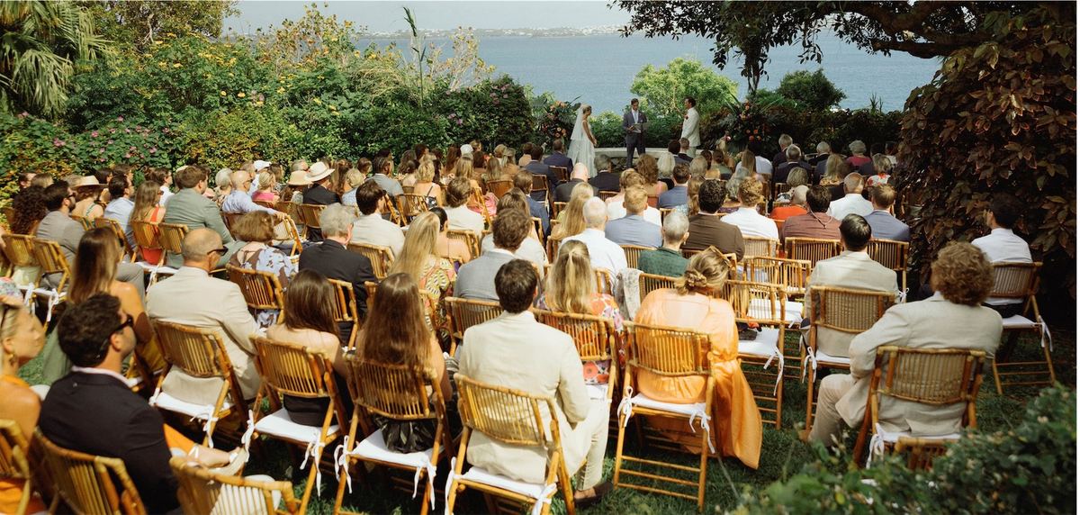 Guests seated in wicker chairs for the garden ceremony above the harbour