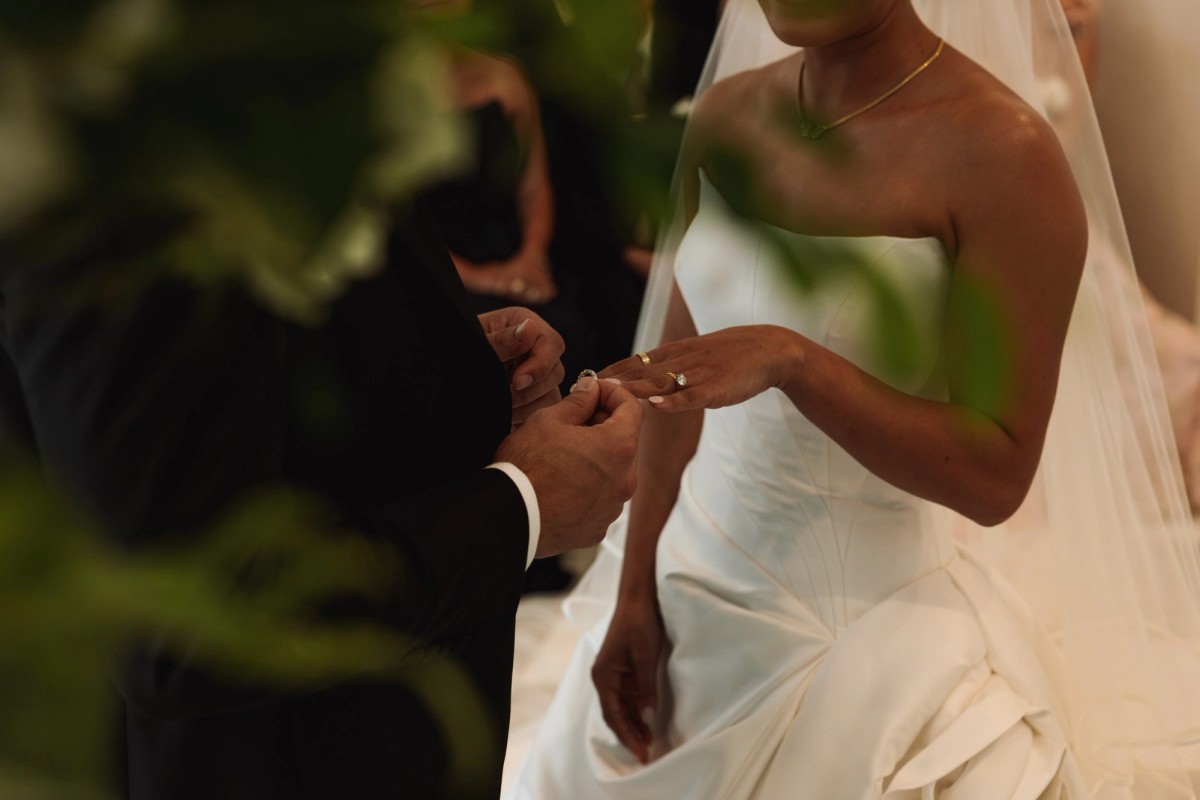 Ring slipped onto the bride's finger seen through greenery at Rosewood Bermuda