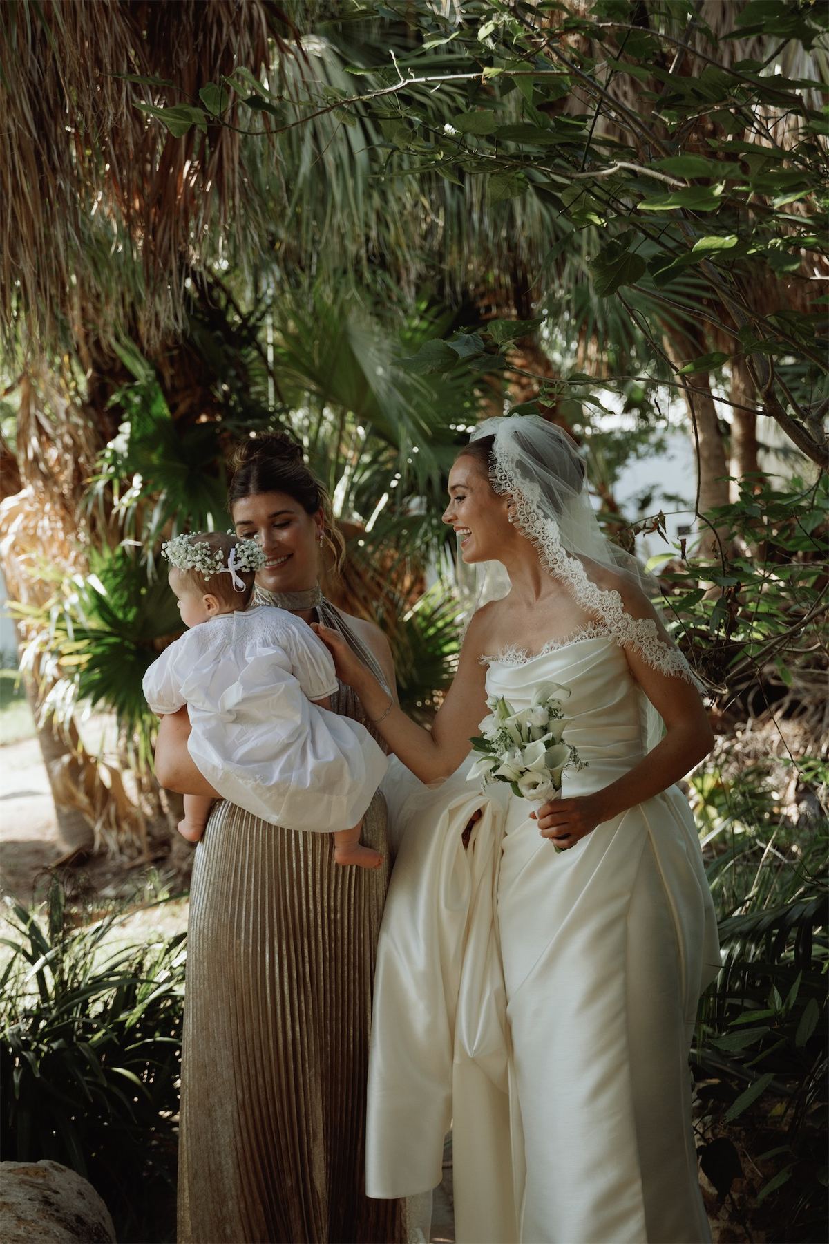 Bride greeting a guest holding a baby in the garden after the ceremony