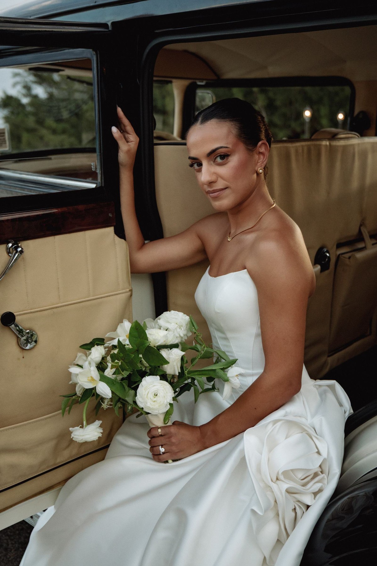 Bride posing in the doorway of a vintage car with her bouquet at Rosewood Bermuda