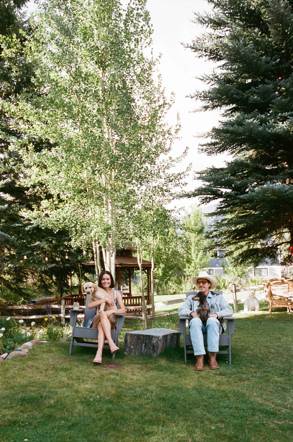 Devin and a guest in Adirondack chairs on the lawn with the dogs, shot on film at a mountain ranch among the aspens