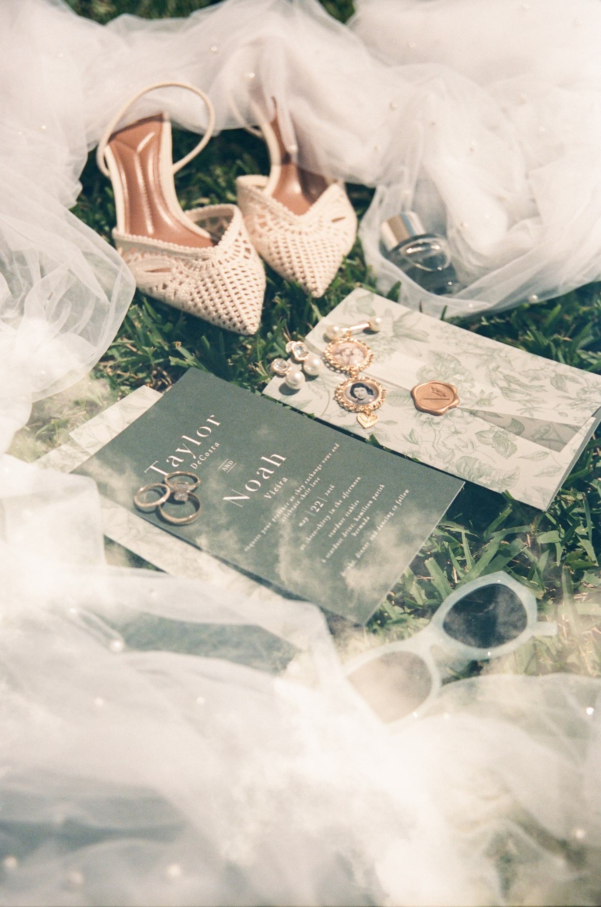 Flat lay of the wedding shoes, invitation, rings and veil on the grass, shot on film