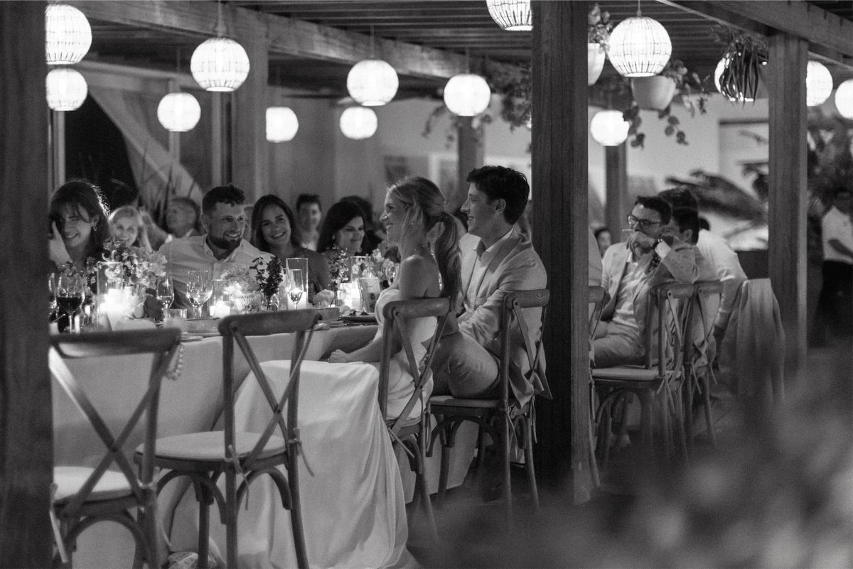 Black and white view down the reception table as guests dine under paper lanterns