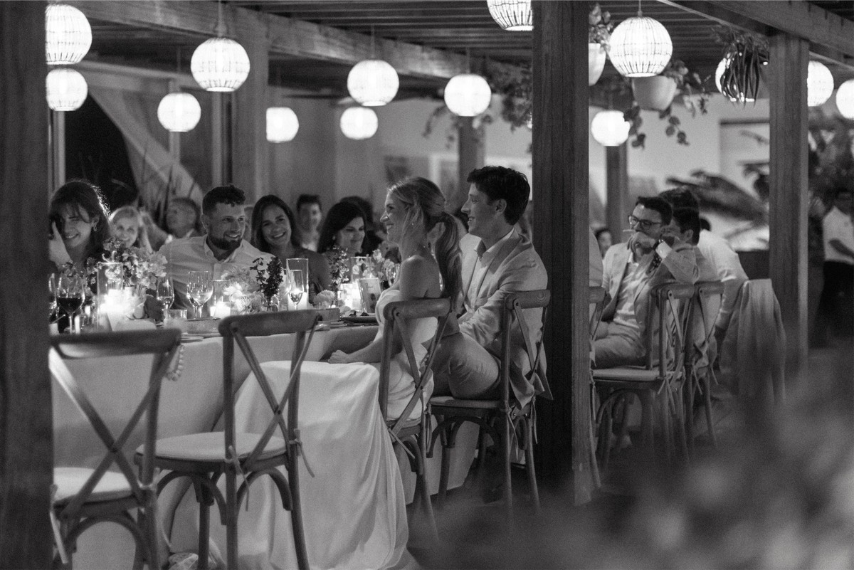Black and white view down the reception table as guests dine under paper lanterns