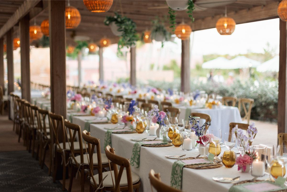 Long reception table set with pastel florals, candles and amber glassware