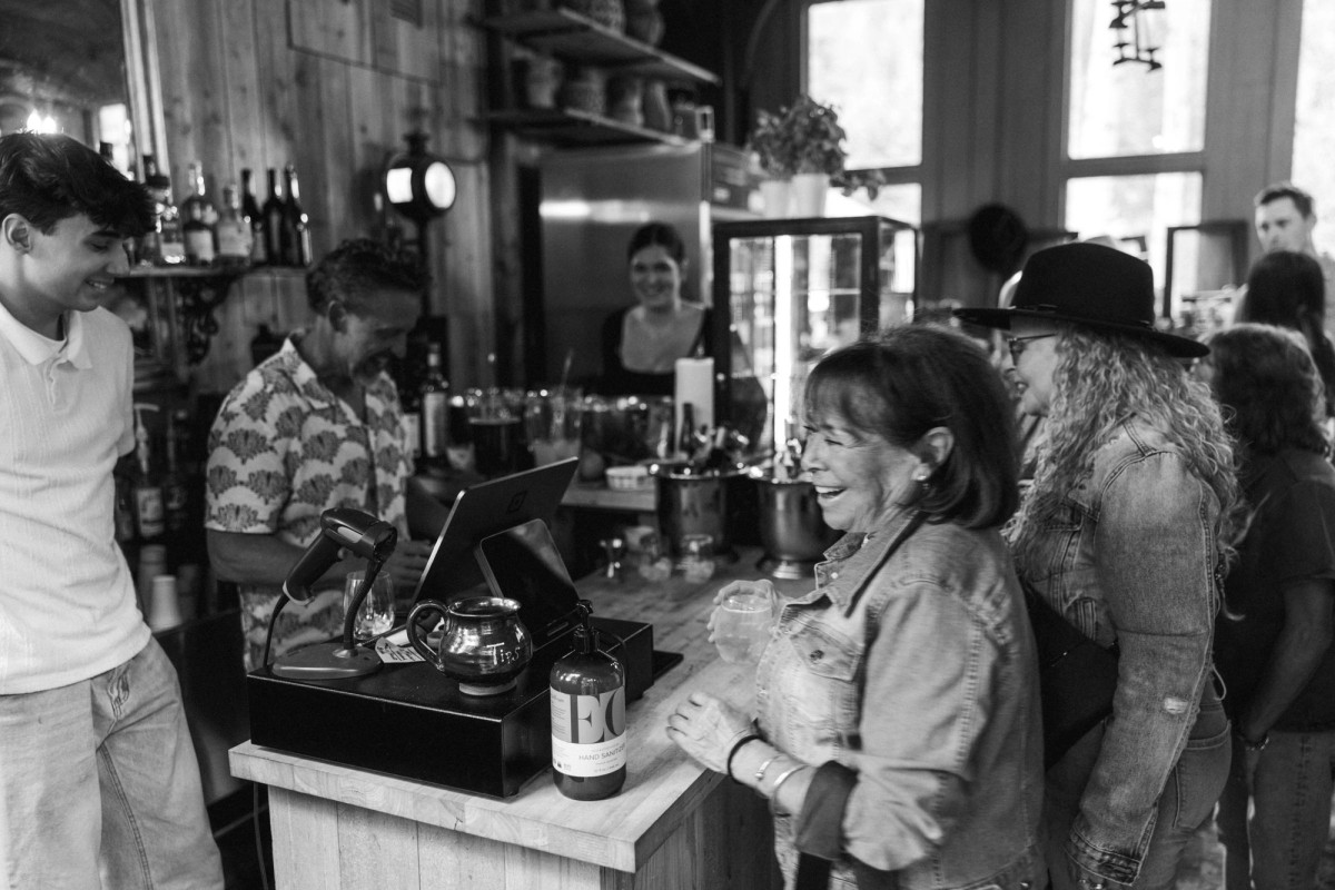 Family laughing around the bar at the welcome dinner at a mountain ranch among the aspens, black and white