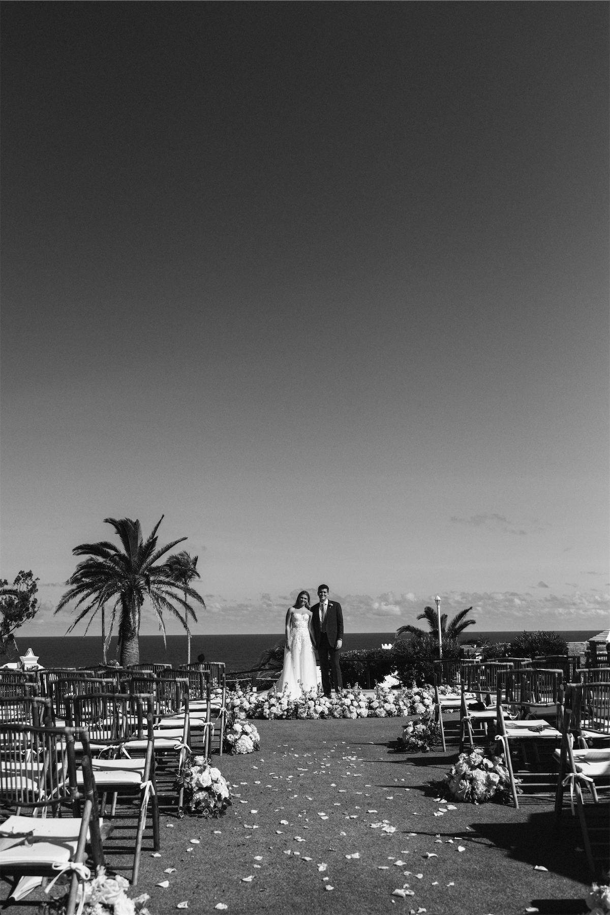 Black and white view of empty ceremony chairs facing the sea at dusk