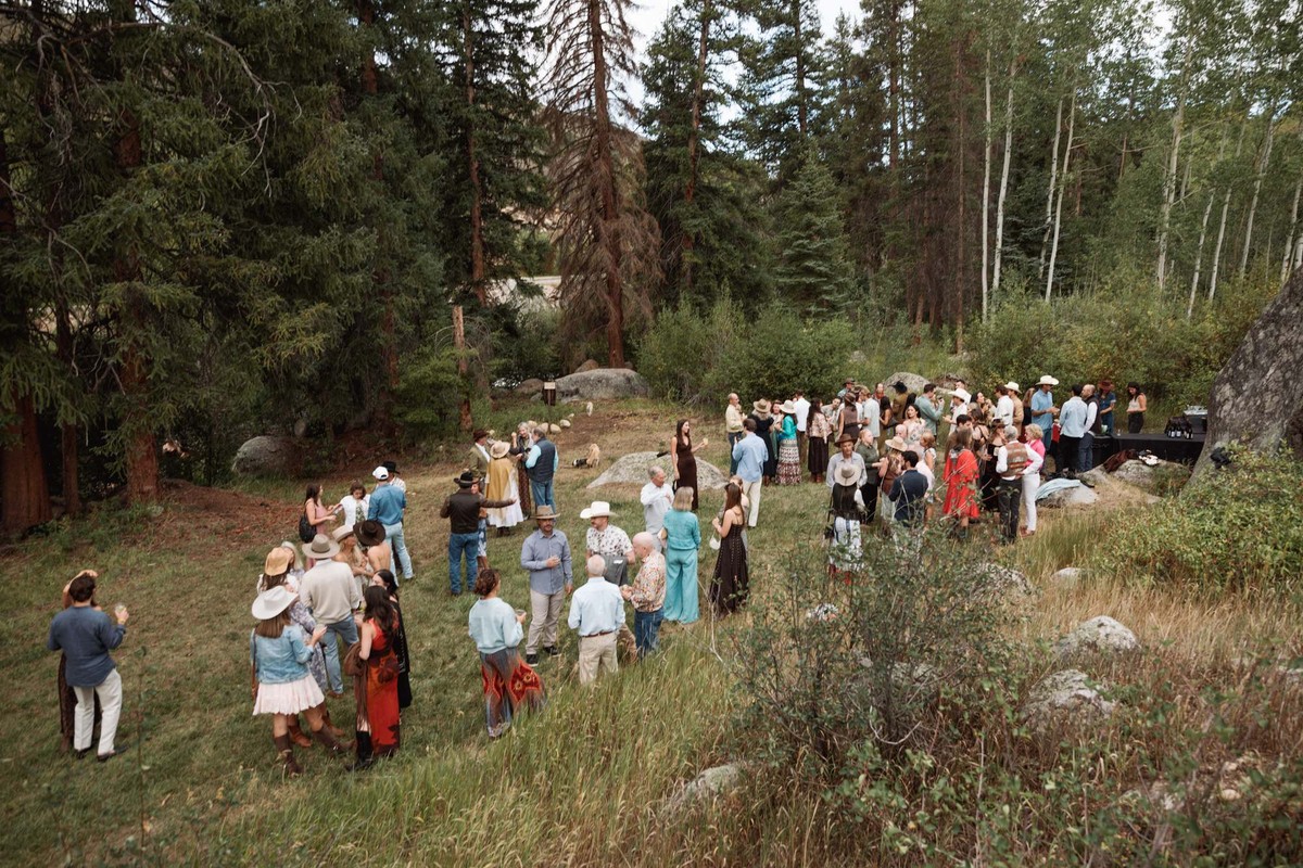 Guests gather on the hillside meadow for the welcome party at a mountain ranch among the aspens