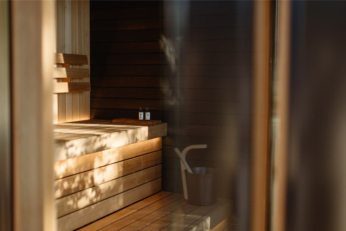 Warm cedar sauna interior with bench, bucket and low evening light