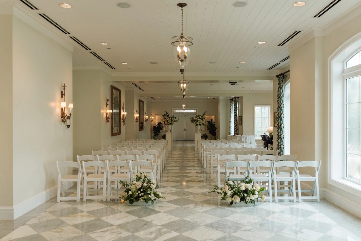 Ceremony room with white chairs, checkered marble floor and white florals at Rosewood Bermuda