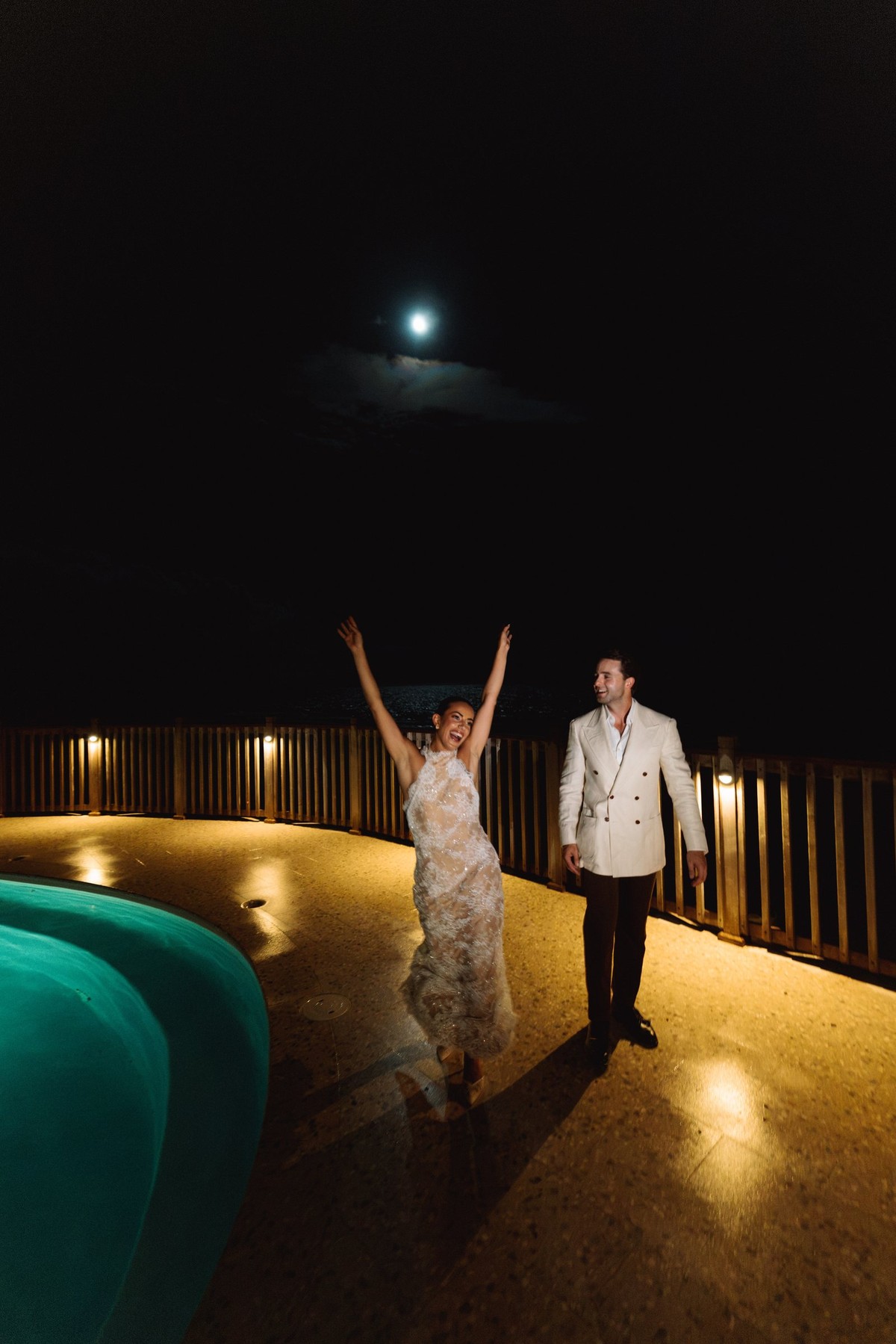 Bride throwing her arms up beside the pool under the moon at Rosewood Bermuda