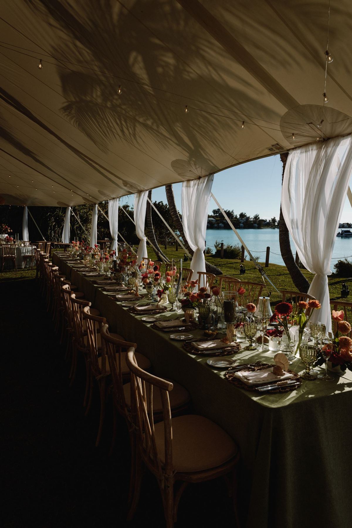 Long banquet table set under a sailcloth tent overlooking the Bermuda ocean