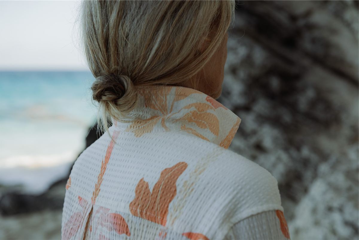 Back detail of a printed textured shirt with turquoise water behind