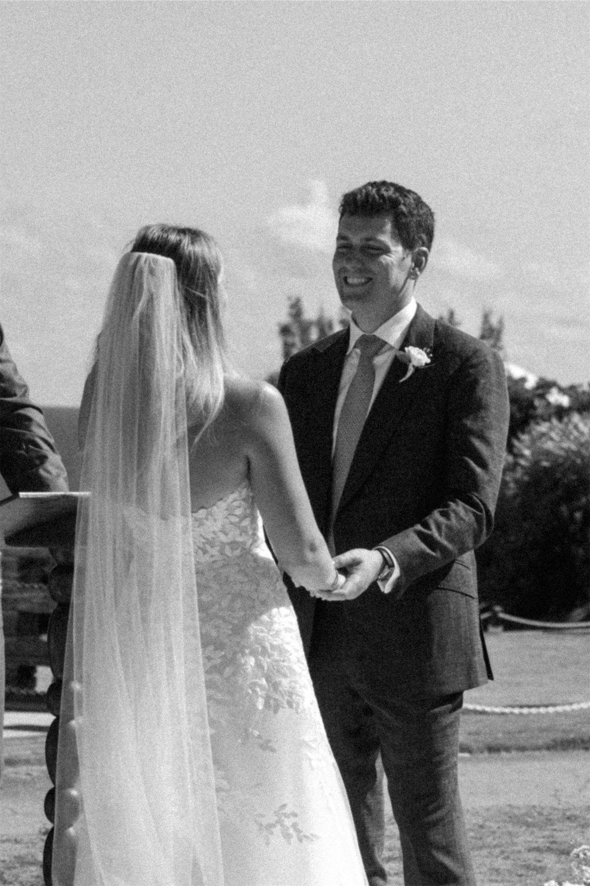 Black and white of the bride and groom holding hands during their vows