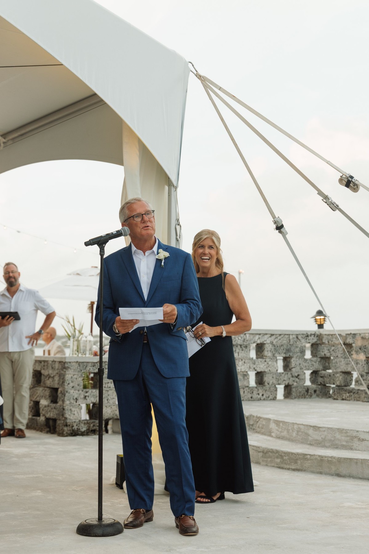 Paige's father gives a speech under the tent with the water behind on Hawkins Island, Bermuda