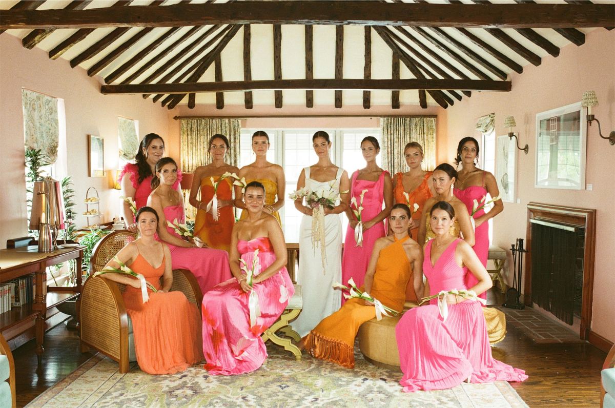 Wedding party in pink and orange gathered in a beamed pink sitting room