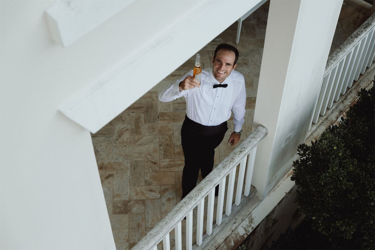 Guest in black tie raising a glass on a white staircase