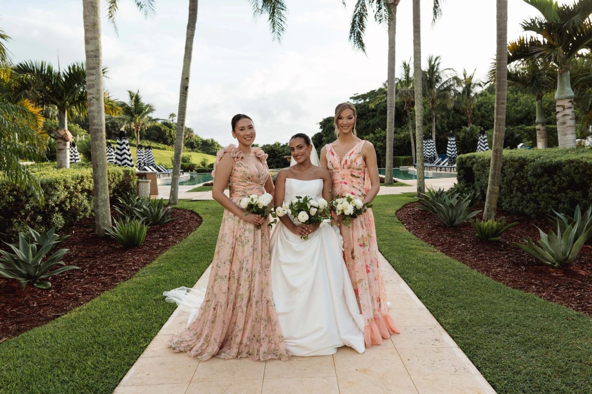 Bride with her bridesmaids in floral pink gowns among the palms at Rosewood Bermuda