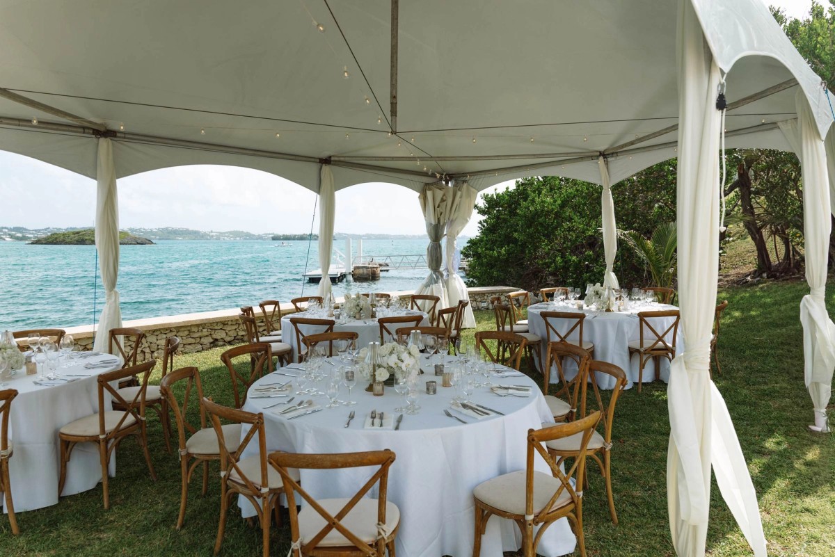 Round tables dressed in white under the open tent facing the bay on Hawkins Island, Bermuda