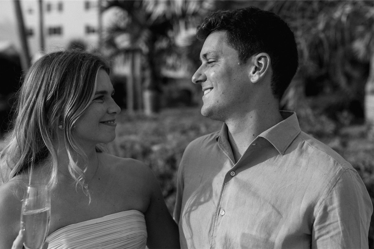 Black and white of the bride laughing with a guest over champagne