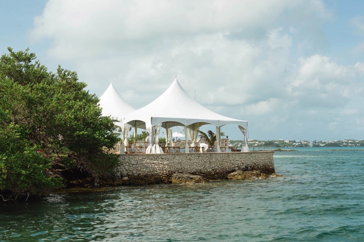 White peaked tents on the stone point above the turquoise water on Hawkins Island, Bermuda