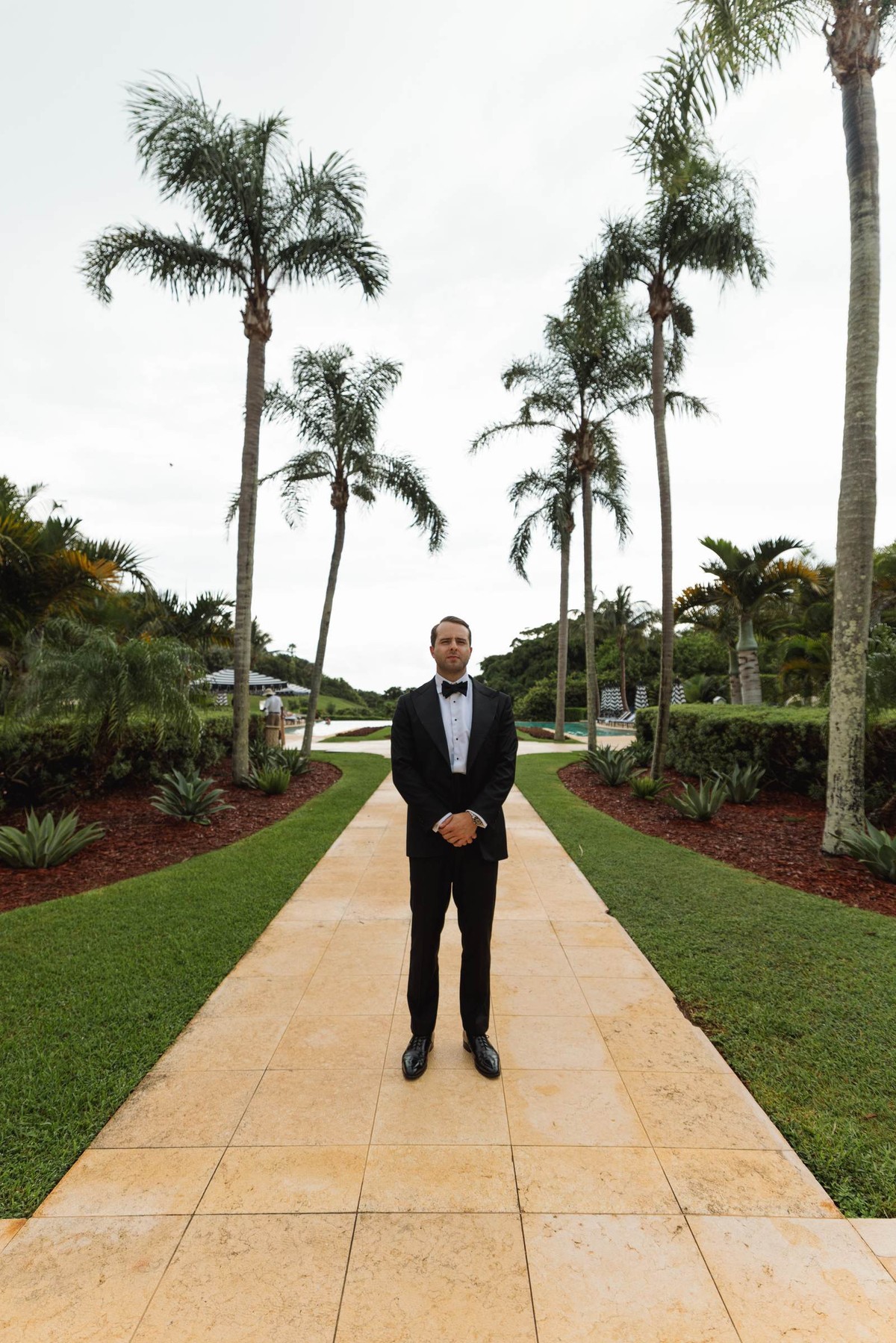 Groom waiting alone on a palm lined path before the first look at Rosewood Bermuda