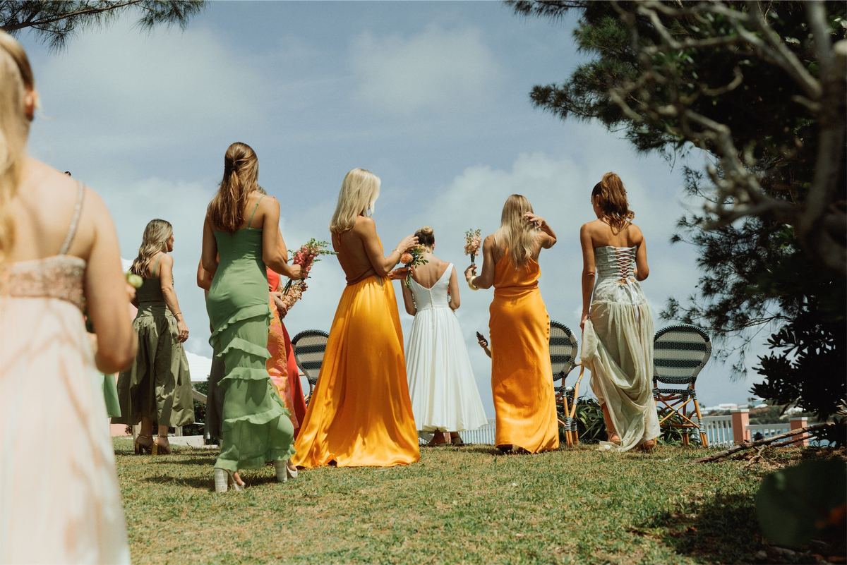 Bridesmaids in silk gowns gathered on the clifftop lawn above the sea
