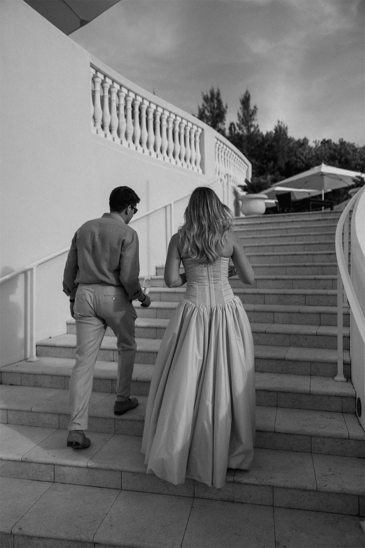 Black and white of the bride and groom climbing a balustraded outdoor staircase