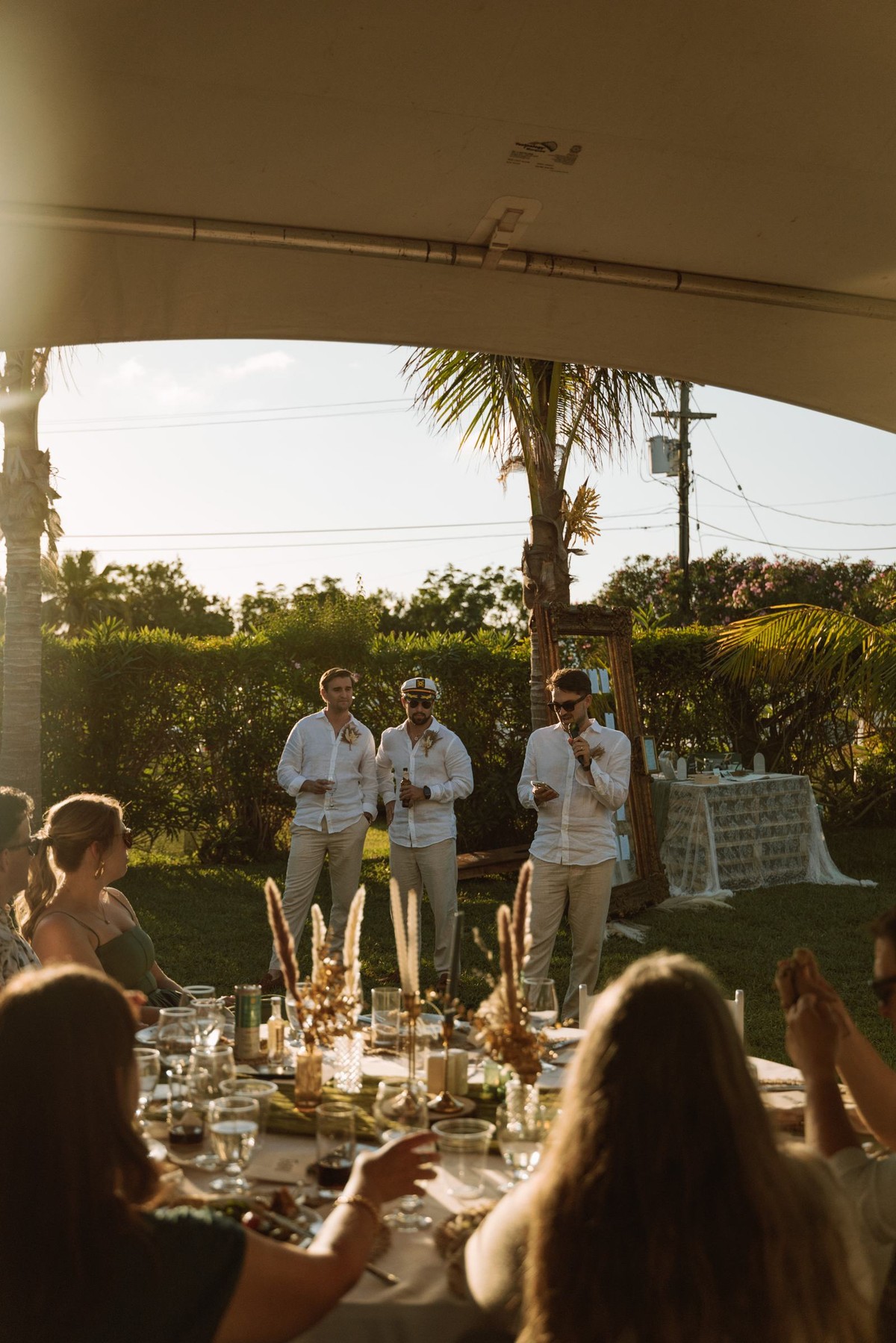Guests raising a toast at the long reception table in the golden hour