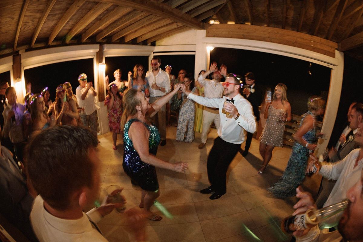 Wide dance floor energy with hands raised at Bermuda wedding reception